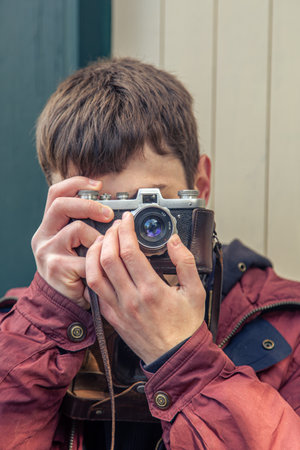 A young man takes pictures on a vintage camera. Film camera photography.の写真素材