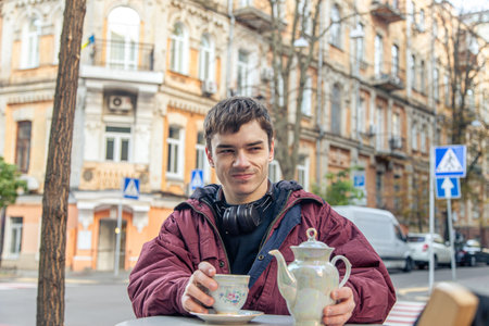 Handsome man drinking tea in the city. A man drinks tea in a cafe.の写真素材
