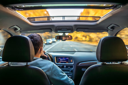 Driving the modern car on asphalt road. A young man drives a car.の写真素材