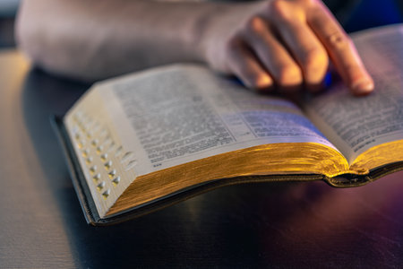 A man reads the Bible. Male hands on the Holy Bible. Close-up of the Bible.の写真素材