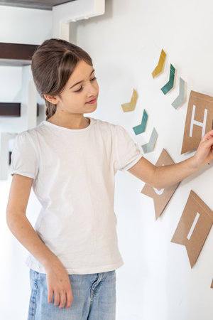 Preparation for the birthday. Girl hangs Happy Birthday sign on a wall.の写真素材