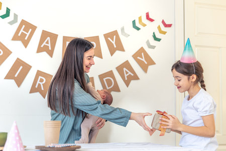 Mother and daughter unwrap a gift. Birthday party at home.の写真素材