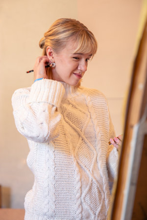 A serious and concentrated woman artist. Artist painting at easel.の写真素材