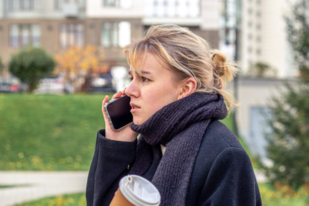 Angry and stressed young woman talking on the phone in the city.の写真素材