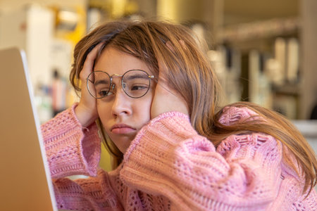 Tired teenage girl working on laptop. Online education. Emotions concept.の写真素材