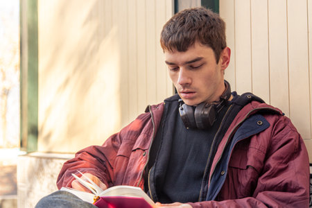 A young man reads a book in a coffee shop. Reading a book outdoors.の写真素材