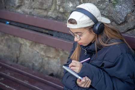 Happy girl in headphones draws in a notebook. Girl in headphones.の写真素材
