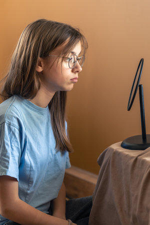 A beautiful girl in glasses looks at herself in the mirror. Morning routine.の写真素材