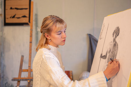 Young female artist painting on easel in studio. Art concept. A woman draws.の写真素材