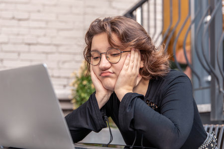 Sad and tired young woman working on laptop. Emotion concept.の写真素材