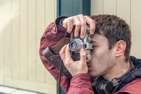 A young man takes pictures on a vintage camera. Film camera photography.の写真素材