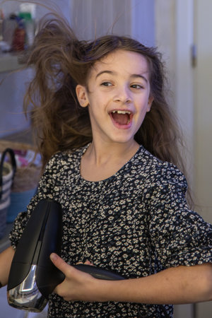 A girl dries her hair with a hairdryer in the bathroom. Hygiene concept.の写真素材