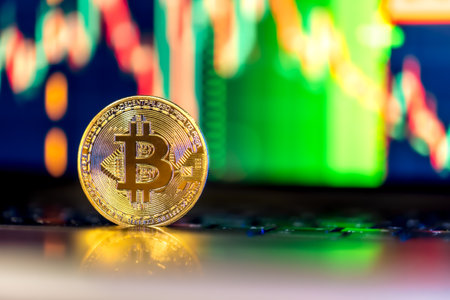 Golden Bitcoin coin on keyboard. Stock market trading chart online candlestick.の写真素材