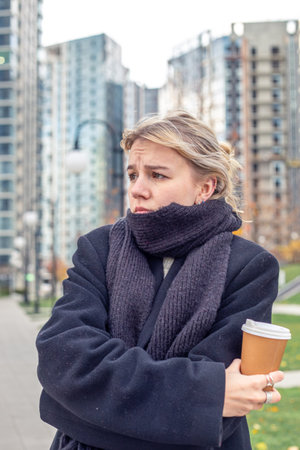 Sad young woman in the city. The woman is cold outside. A walk in the city.の写真素材