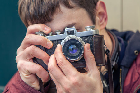 A young man takes pictures on a vintage camera. Film camera photography.の写真素材