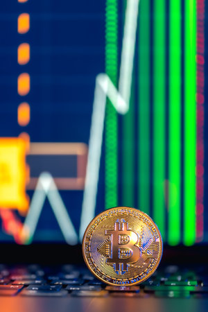 Golden Bitcoin coin on keyboard. Stock market trading chart online candlestick.の写真素材