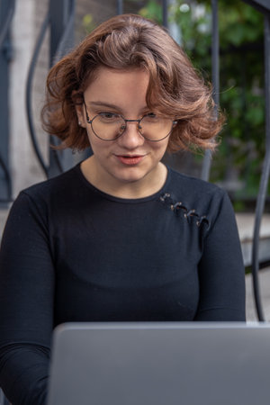 A happy girl is working on a laptop. A girl with a laptop. Emotion concept.の写真素材
