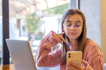 Happy girl taking selfie while working on laptop. A girl with a phone.の写真素材