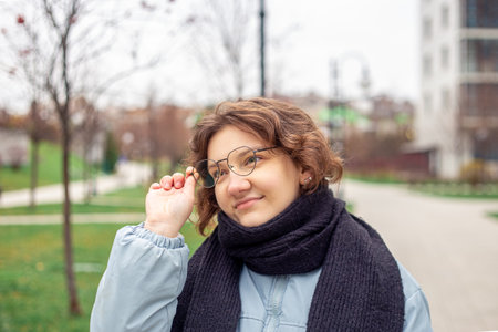 Portrait of a beautiful young woman holding glasses in her hand in the city.の写真素材