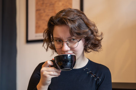 Sad girl with coffee in hands. Emotion concept. The emotion of sadness.の写真素材