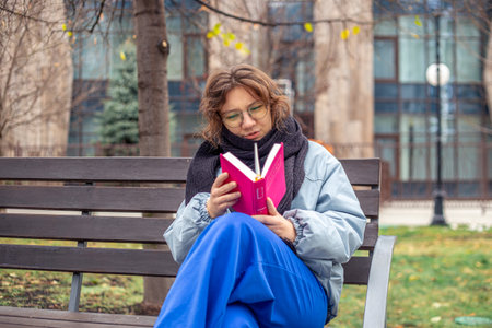 Girl reading a book on the street close-up. Teenage girl reading a book.の写真素材