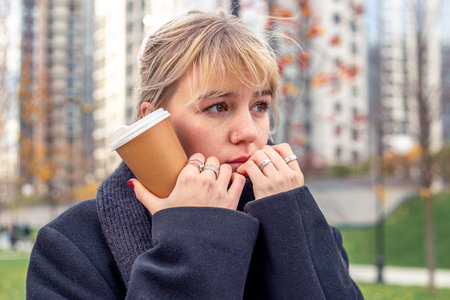 Sad young woman in the city. The woman is cold outside. A walk in the city.の写真素材