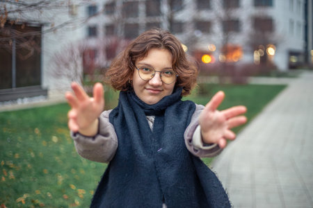 Young woman reaching her hand to the camera. Girl walks through the city.の写真素材