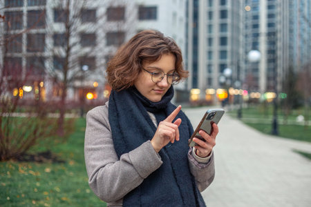 A teenage girl uses a phone in the city. Girl in the city. Technology concept.の写真素材
