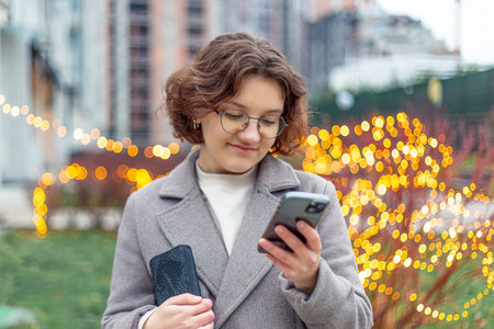 A teenage girl uses a phone in the city. Girl in the city. Technology concept.の写真素材