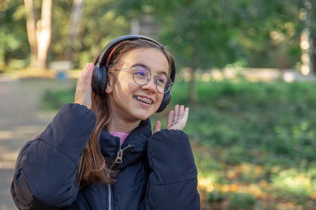 A happy girl is listening to music in headphones on a walk.の写真素材