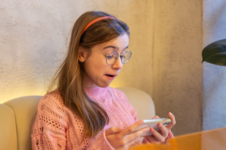 Surprised teenage girl playing games on the phone. Emotions concept.の写真素材