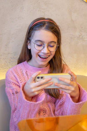 Happy teenage girl playing games on the phone. Emotions concept.の写真素材