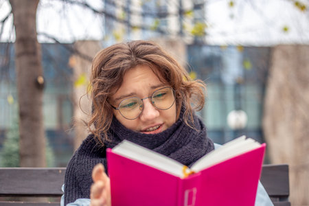 Girl reading a book on the street close-up. Teenage girl reading a book.の写真素材