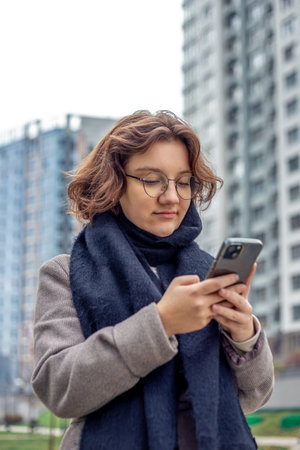 A teenage girl uses a phone in the city. Girl in the city. Technology concept.の写真素材