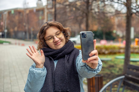 Teenage girl talking on video call outside. Woman in the city.の写真素材