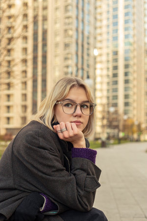 A woman sits contemplatively on a bench outside. Woman in the city.の写真素材