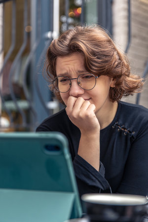 Sad young woman watching sad video on tablet. Emotion concept.の写真素材