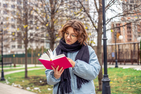 Girl reading a book on the street close-up. Teenage girl reading a book.の写真素材