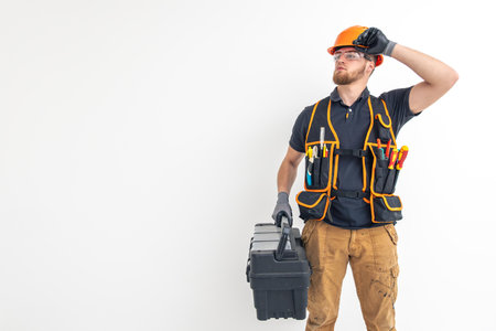 Male builder. Electrical engineer in overalls and helmet holds toolbox in hands. Space for text.の写真素材