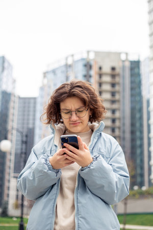 A teenage girl uses a phone in the city. Girl in the city. Technology concept.の写真素材