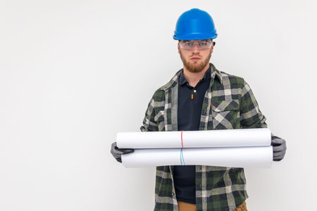 Male builder. Engineer in overalls and helmet holds blueprints and projects in his hands.