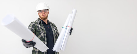 Male builder. Engineer in overalls and helmet holds blueprints and projects in his hands.の写真素材