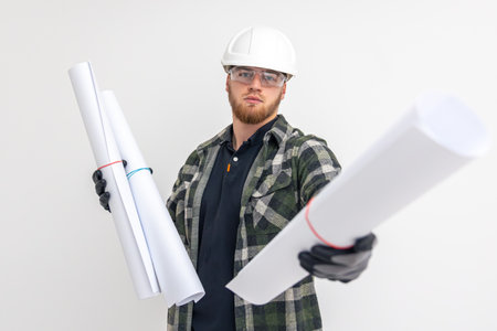 Male builder. Engineer in overalls and helmet holds blueprints and projects in his hands.の写真素材