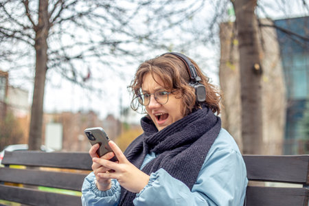 Young woman looking at phone in surprise in the city. A woman in a big city.の写真素材