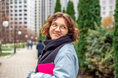 A young girl student with a book in her hands goes to the university.の写真素材