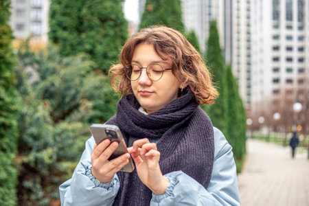 Teenage girl using phone in city. Girl ordering taxi online.の写真素材