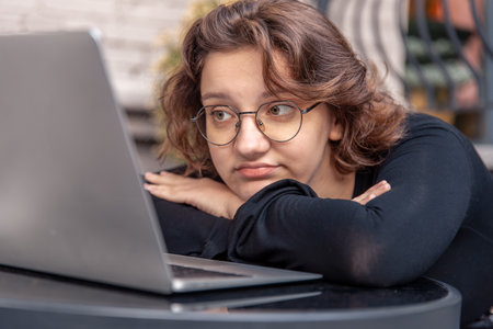Sad and tired young woman working on laptop. Emotion concept.の写真素材