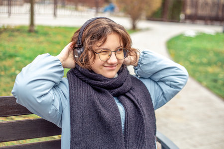 Teenage girl listening to music in headphones in the city. Woman in the city.の写真素材