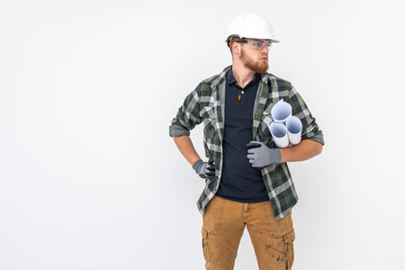 Male builder. Engineer in overalls and helmet holds blueprints and projects in his hands.の写真素材