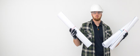 Male builder. Engineer in overalls and helmet holds blueprints and projects in his hands.の写真素材